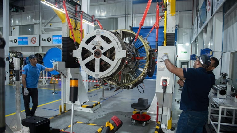 Engineers and workers stand inside Safran Aircraft Engines repair plant...