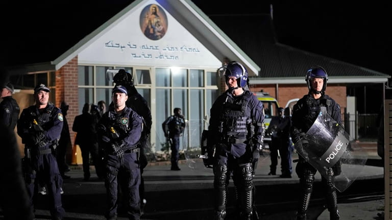 Security officers stand guard outside Orthodox Assyrian church in Sydney,...