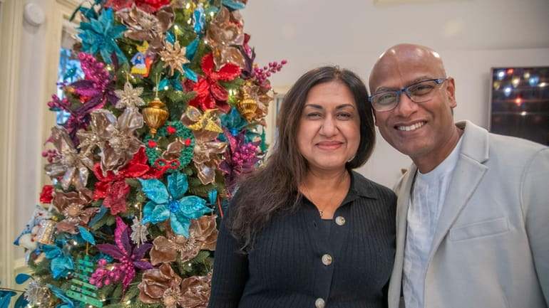 Standing near their brightly decorated holiday tree, Nina Paul and...