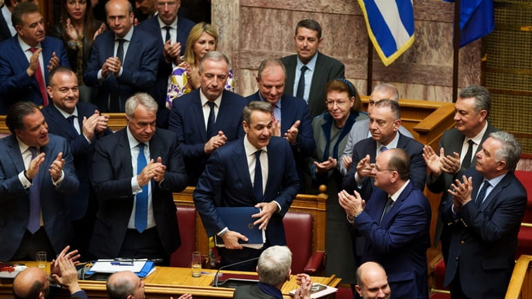 Greece Prime Minister Kyriakos Mitsotakis, center, is applauded by his...