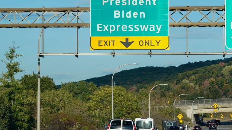 The motorcade of President Joe Biden passes underneath a sign...