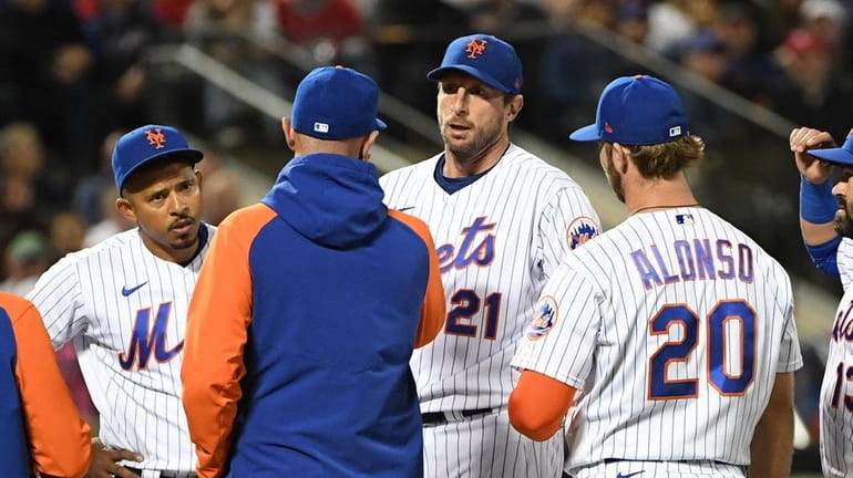 Mets players, pitching coach and a trainer surround starting pitcher...