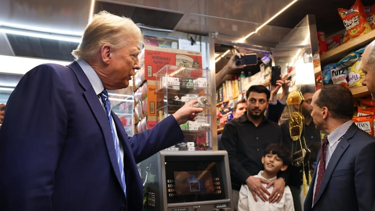 Former president Donald Trump talks with bodega owner Maad Ahmed,...