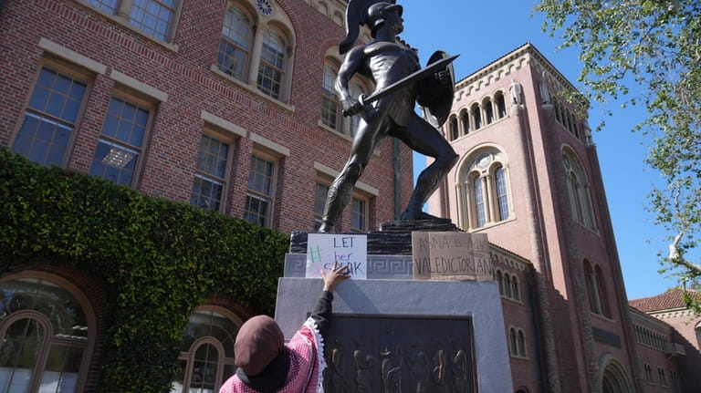 A Pro-Palestinian student places a sign on the Tommy Trojan...