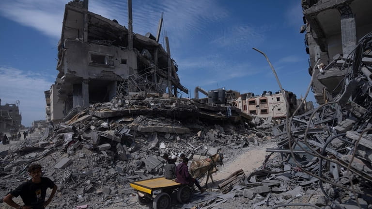 Palestinians walk through the destruction in the wake of an...