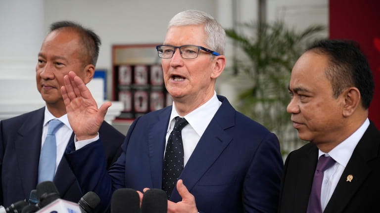 Apple CEO Tim Cook ,center, talks to journalist during a...