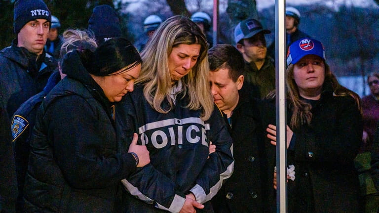 Family members weep during the candlelight vigil for slain NYPD...
