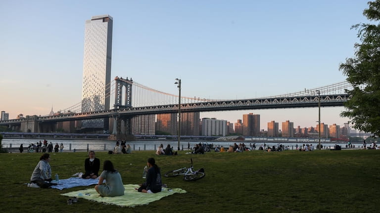 People are seen having a picnic at the Brooklyn Bridge Park...