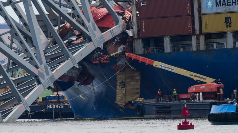 Workers remove wreckage of the collapsed Francis Scott Key Bridge,...