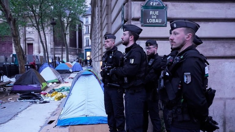 Police officers stand by a makeshift camp during an evacuation...