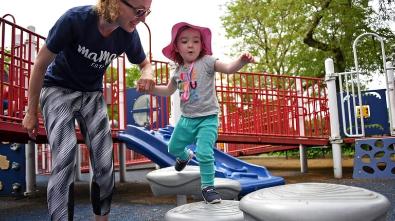Nina Chalson climbs through the playground with some help from...