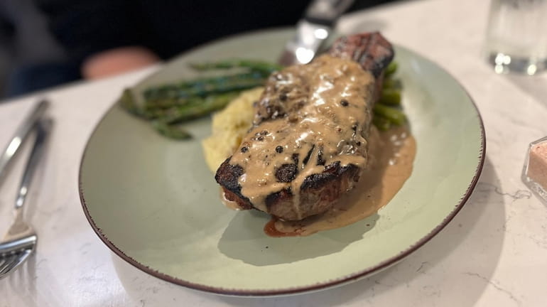 New York strip steak bathed in a zippy peppercorn sauce at...