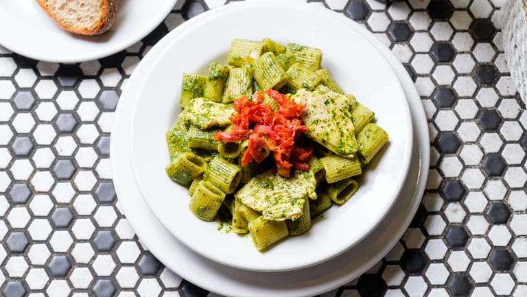 RIgatoni with pesto Genovese and chicken breast is topped with sun-dried...