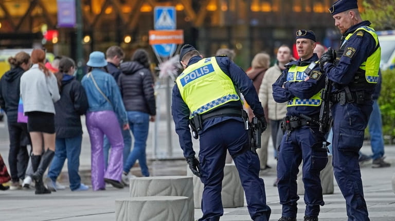 Police stand guard as people queue in line for the...