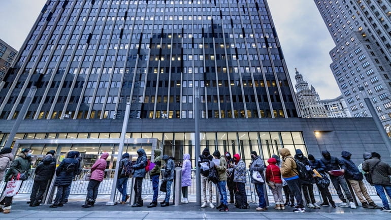 Hundreds of immigrants wait outside a Manhattan immigration office for their...