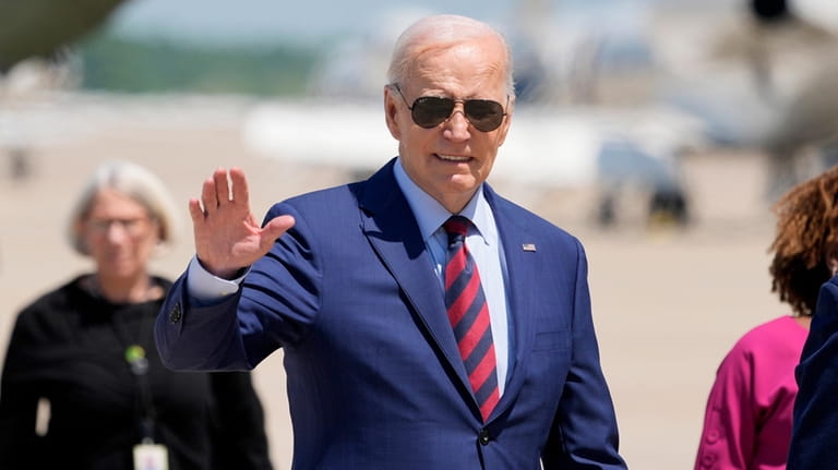 President Joe Biden waves as he walks to board Air...