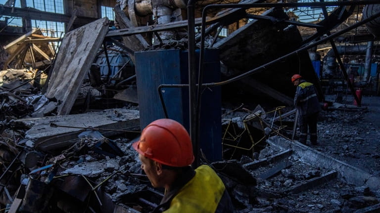 Workers walk among debris in a damaged DTEK thermal power...