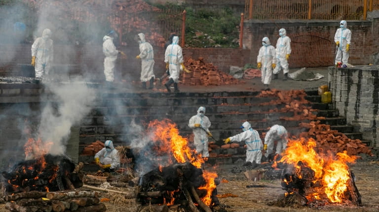 Men in personal protective suits cremate the bodies of COVID-19...