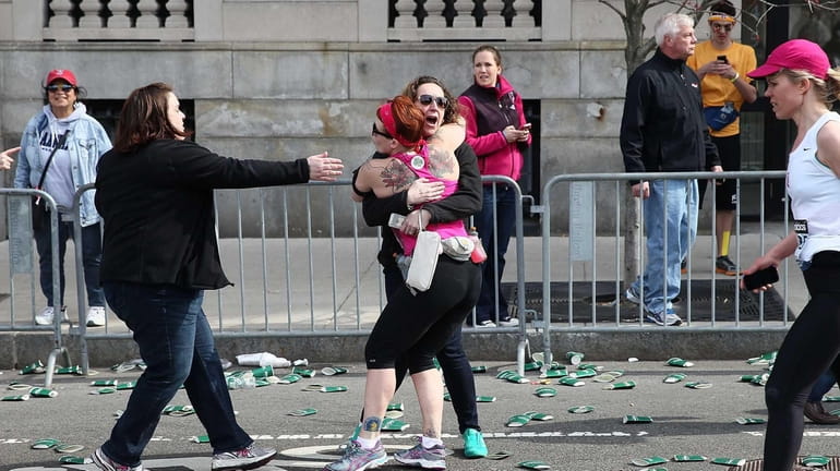 A runner embraces another woman on the marathon route near...