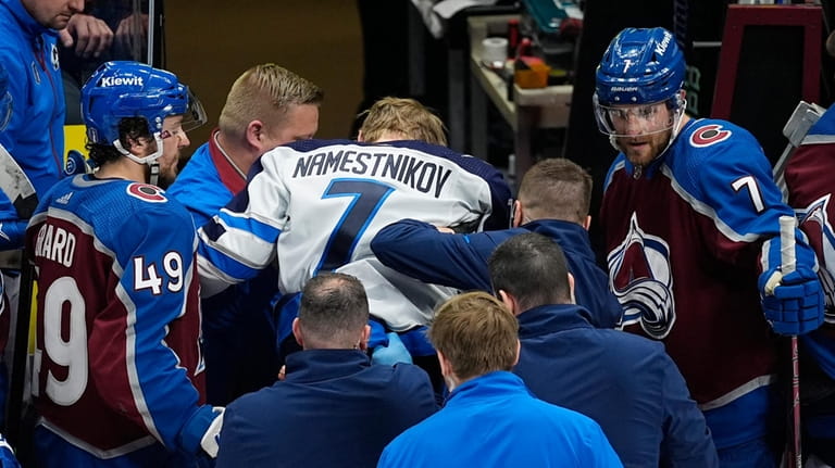 Winnipeg Jets center Vladislav Namestnikov, center, is helped off the...