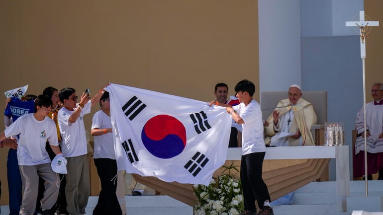 Young pilgrims from South Korea celebrate with their national flag...