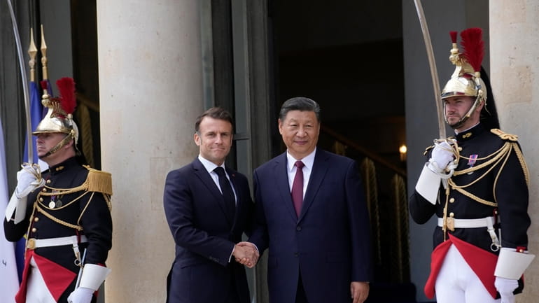 French President Emmanuel Macron shakes hands with China's President Xi...
