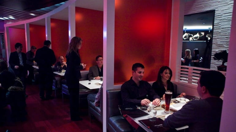 Patrons dine in modern red booths at Two Steak &...