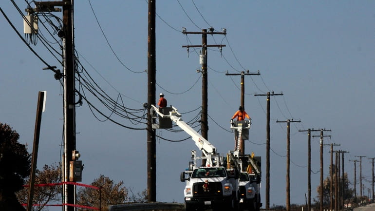 FILE -- Utility crews repair overhead lines along Pacific Coast...