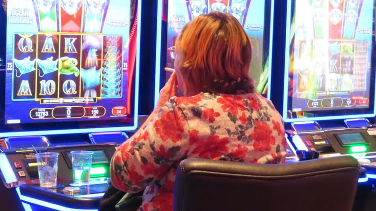 A gambler smokes while playing a slot machine at the...