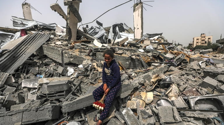 A Palestinian girl sits among the rubble of a house...