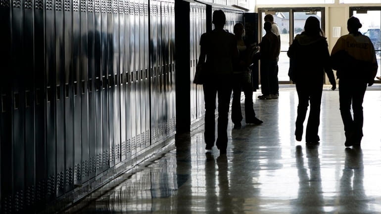 Students walk down a hallway at a high school in...