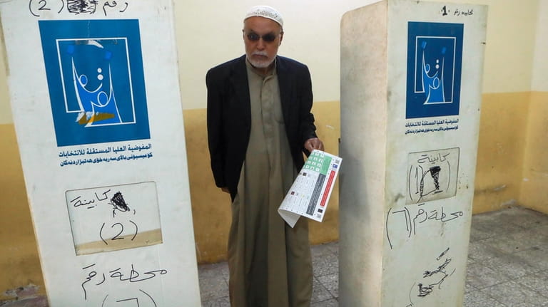 An elderly Iraqi man casts his vote in the country's...