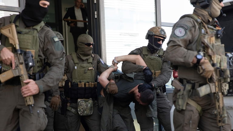 Kosovo police members of Special Intervention Unit escort one of...
