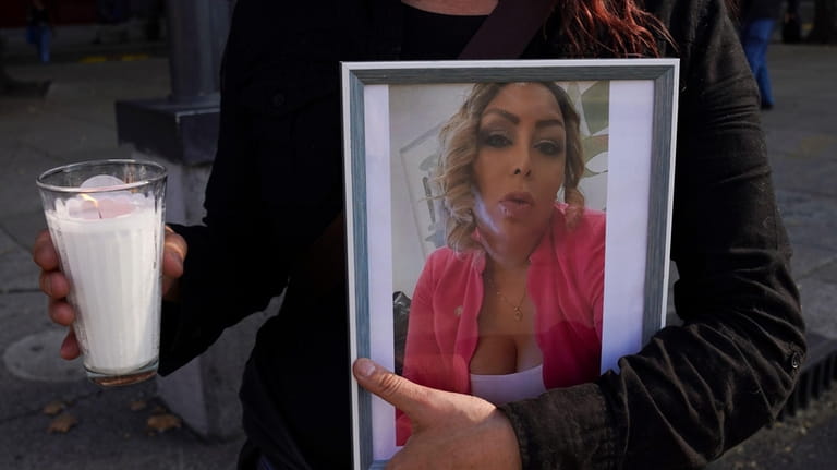A member of the LGBTQ+ community holds a portrait of...