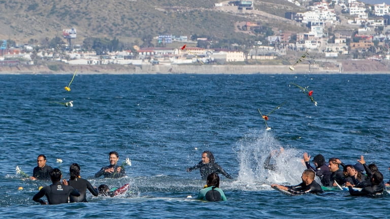 Surfers throw flowers during a tribute to 3 missing surfers...
