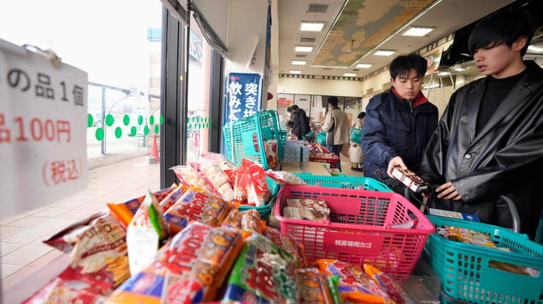 People shop for food items at a supermarket that has...