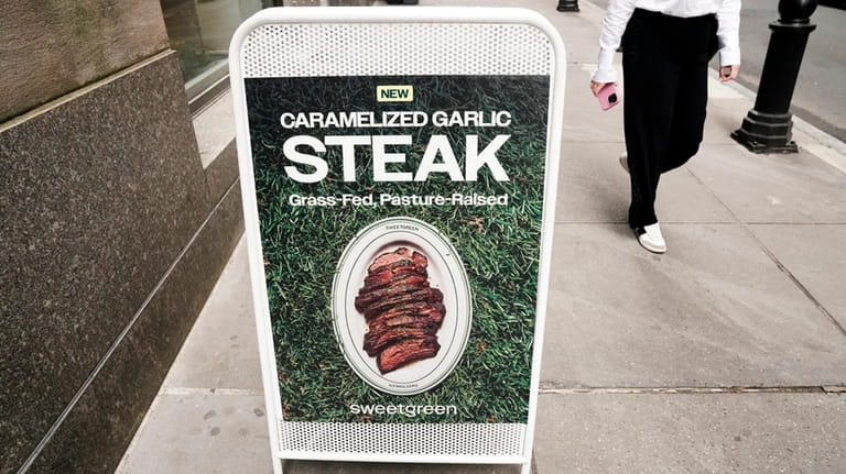 A person walks past a sign for Sweetgreen's new caramelized...