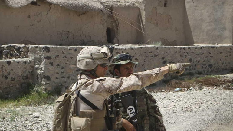 A U.S. Marine on a joint patrol with an Afghan...