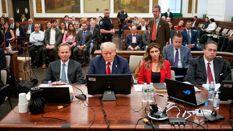 Former President Donald Trump, center, sits in the courtroom with...