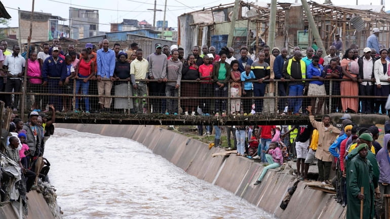 People stand on a bridge, as they watch houses in...
