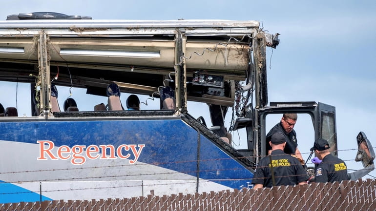 Investigators examine the tour bus that crashed last month while taking...