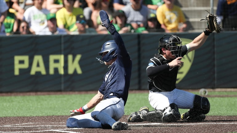 Oral Roberts utility Jonah Cox, left, slides home to score...