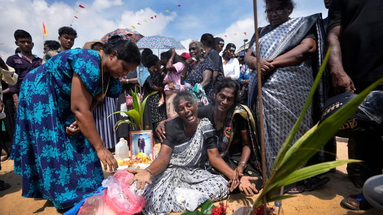 An ethnic Tamil war survivor is consoled by others as...