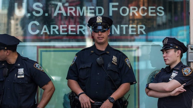New York City Police officers stand guard at a military...