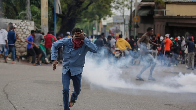 A protester run from tear gas fired by riot police...