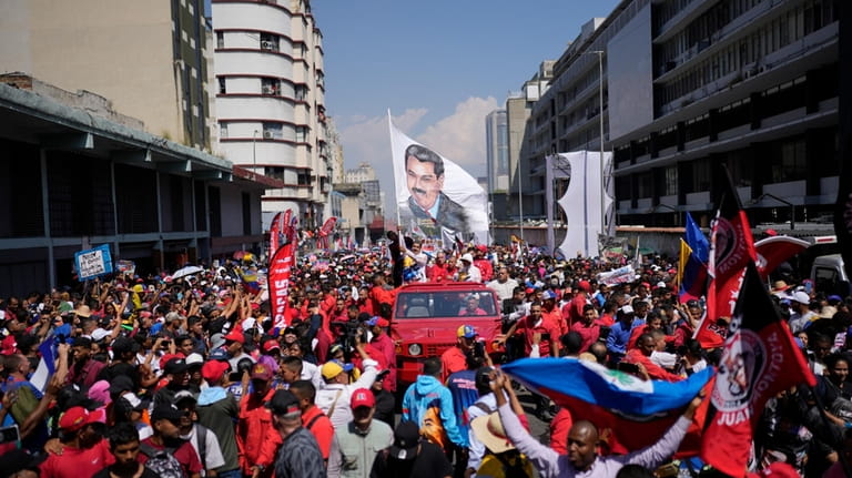 Venezuelan President Nicolas Maduro waves a flag of himself as...