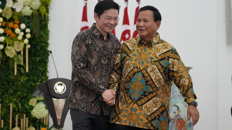 Indonesian Defense Minister and president-elect Prabowo Subianto, right, shakes hands...