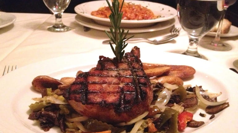 A center-cut pork chop garnished with hot peppers, mushrooms and...