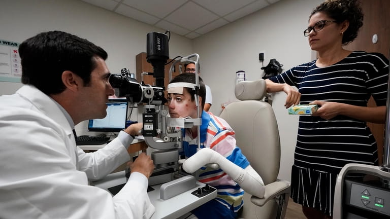 Dr. Alfonso Sabater, left, examines Antonio Vento Carvajal's eyes accompanied...
