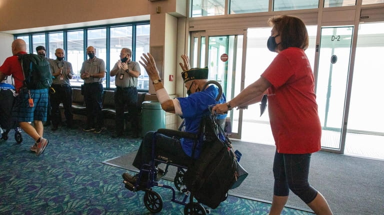 Airport employees applaud as World War II veteran Dominick Critelli...